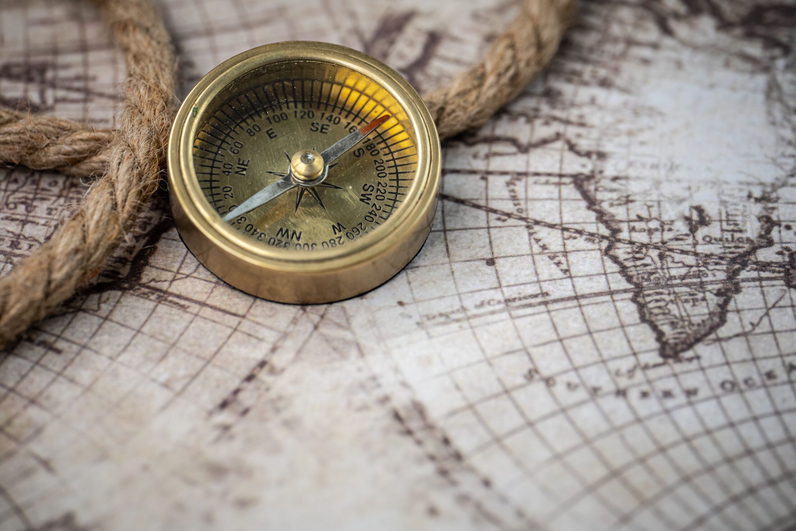 Close-up of a brass compass on an old world map.
